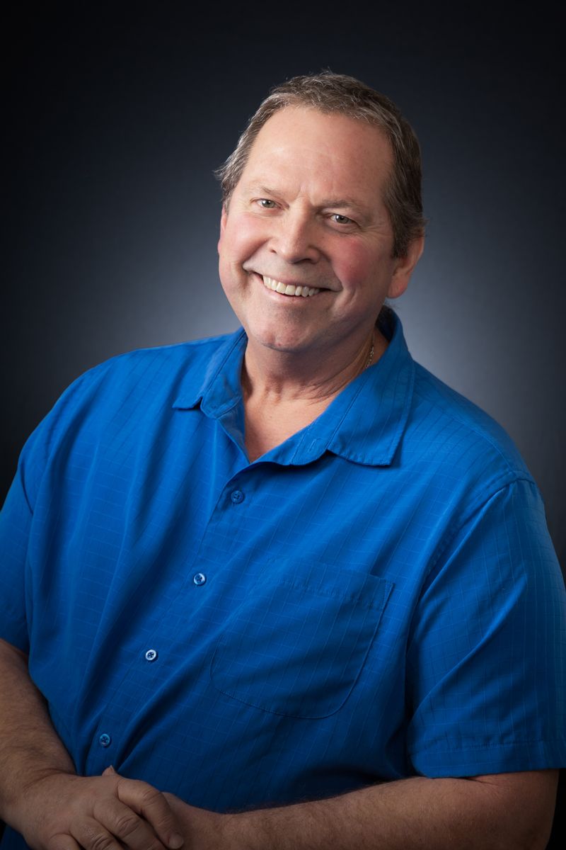 Headshot of a smiling man in a blue shirt