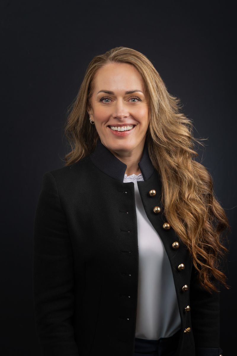 Headshot of a woman with long wavy hair in a dark jacket